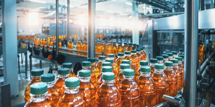 High-speed production line with amber juice bottles on conveyor