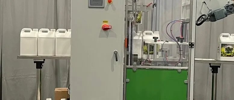 Technician servicing CeltheQ sleeve labeling machine with bottles on conveyor