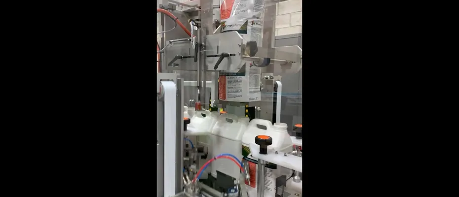 Close-up of CeltheQ labeling machine processing white jugs