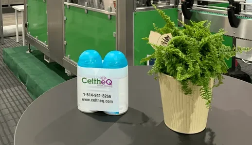 CeltheQ branded bottle with plant and sleeve labeling machine in background